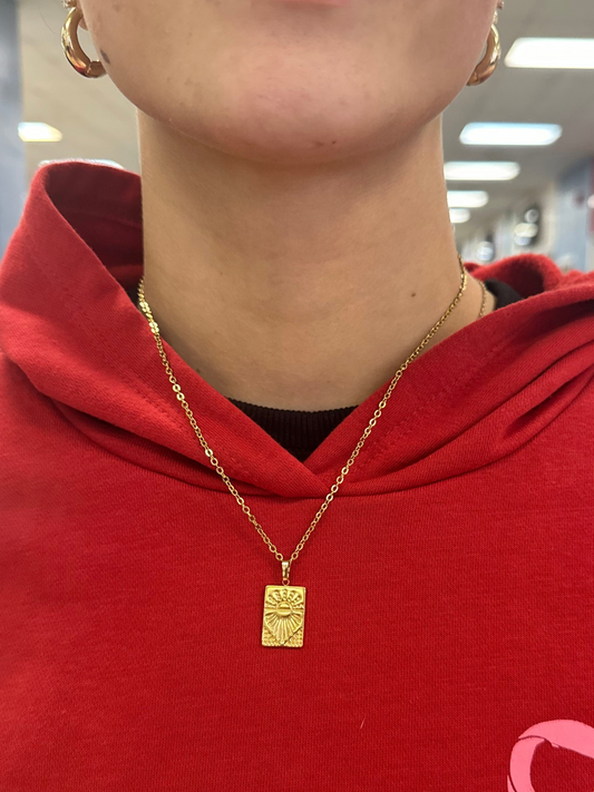 Person wearing a red garment with a pink bow design, gold necklace, and visible jewelry.