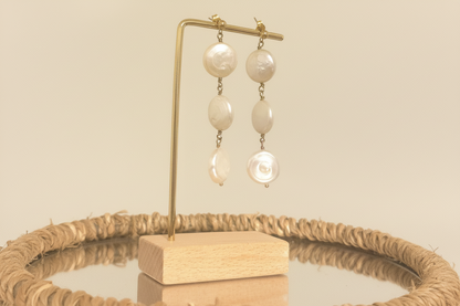 Pearl earrings on a gold stand with a beige background
