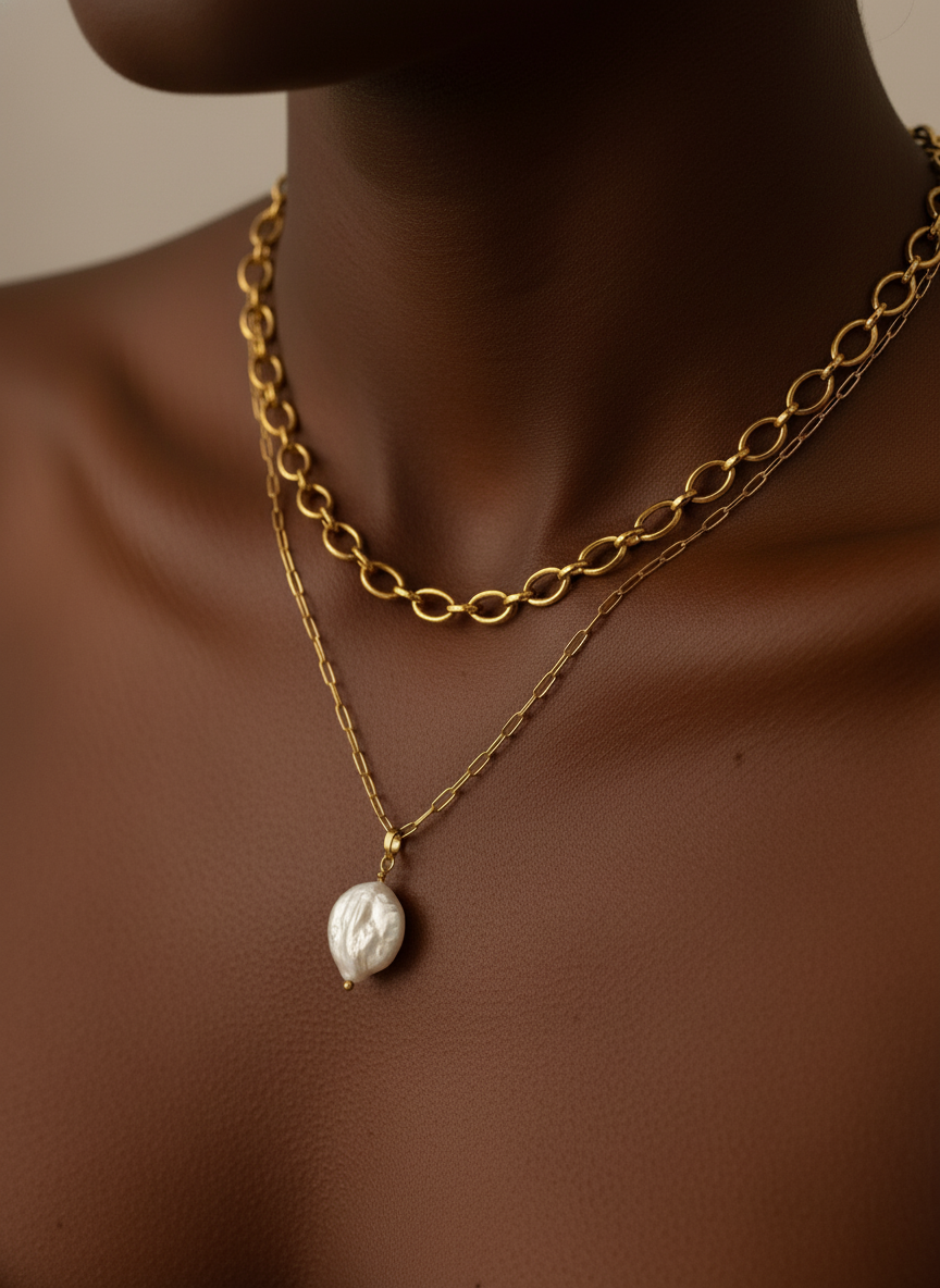 Gold chain necklace with a pearl pendant on a person's neck against a neutral background