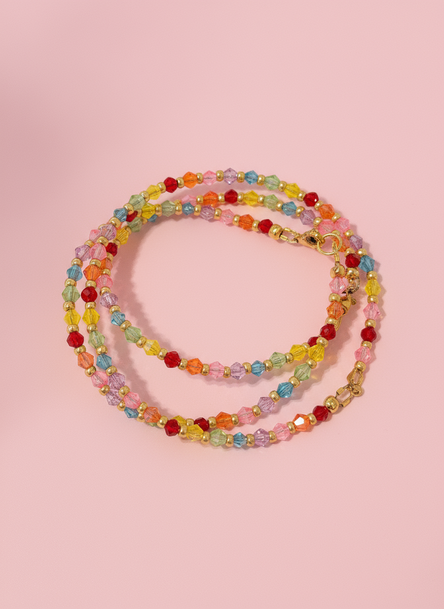 A multicolored beaded bracelet with a variety of colorful glass crystals and gold beads, displayed on a shell-like surface.