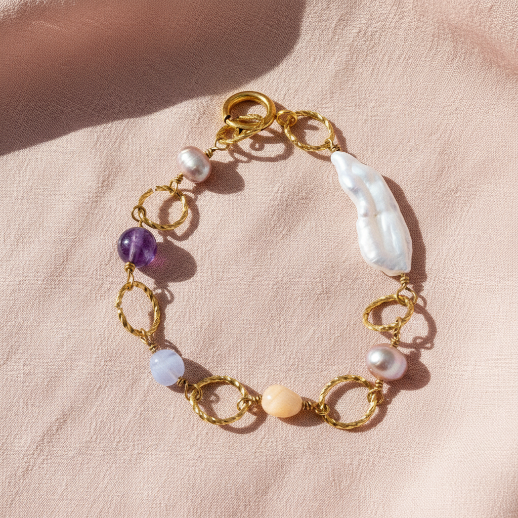 Bracelet with gold chain, pearls, and amethysts on a pink fabric background