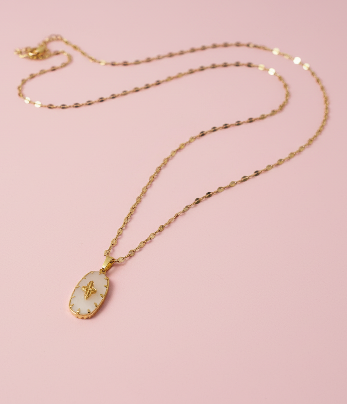 Gold necklace with a pendant on a pink background