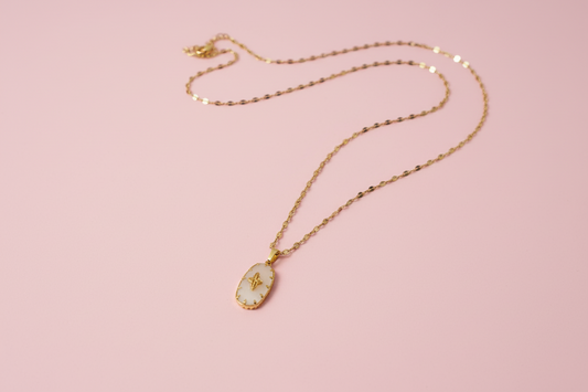 Gold necklace with a pendant on a pink background