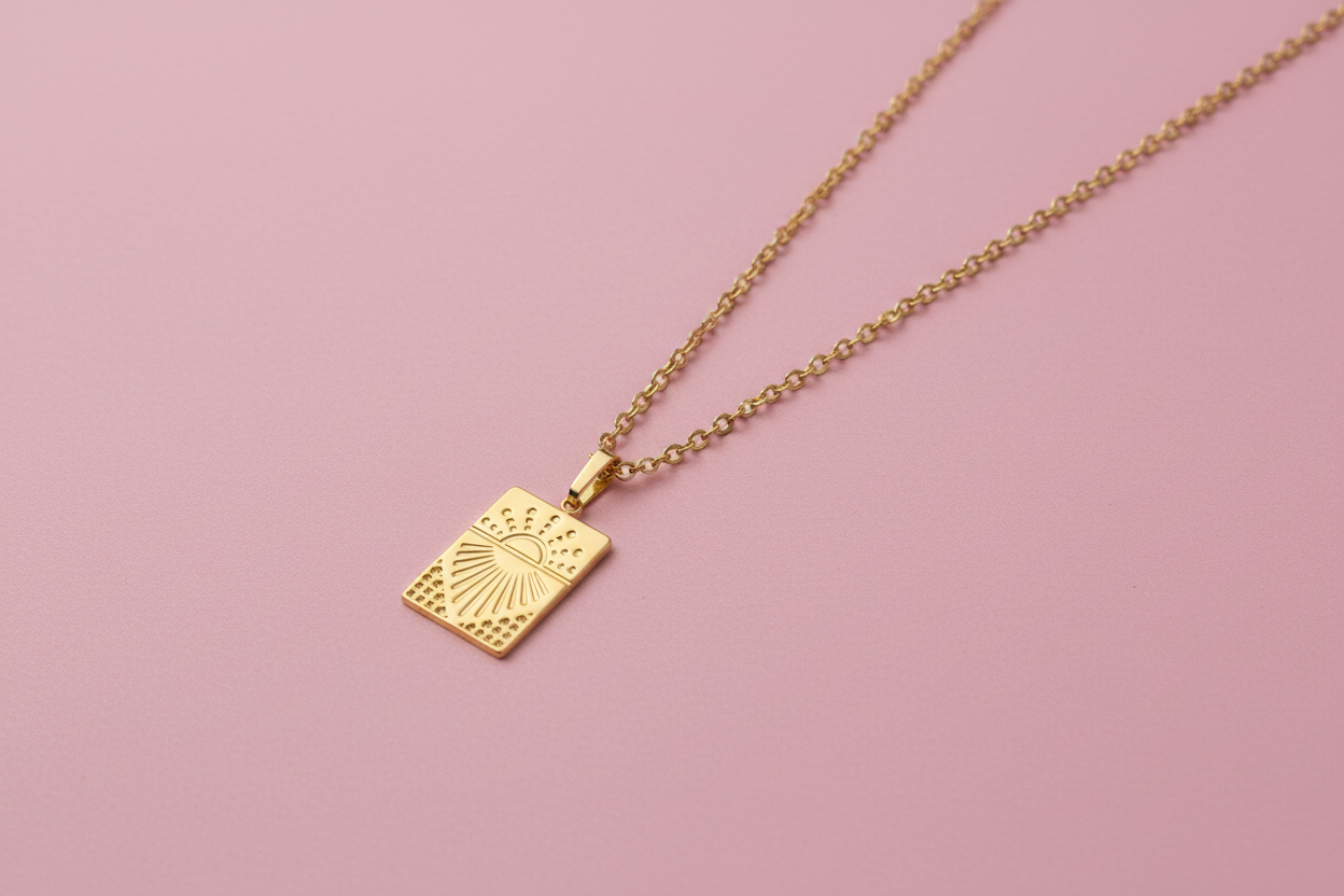 Gold necklace with a square pendant on a pink background
